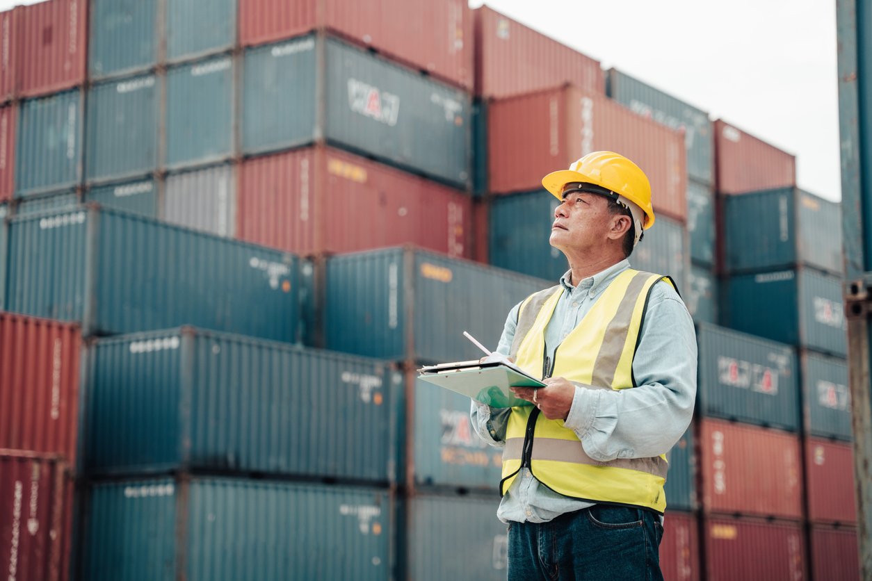 Male foreman wearing a helmet inspects the order of the container. and plan the placement of containers.